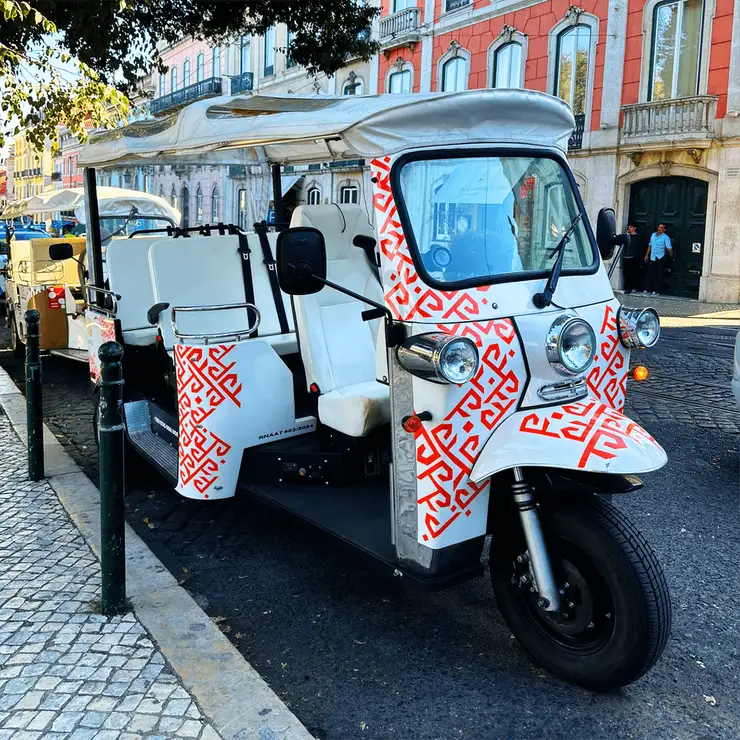 A MAZE electric tuk-tuk parked kerbside in front of colourful Lisbon façades
